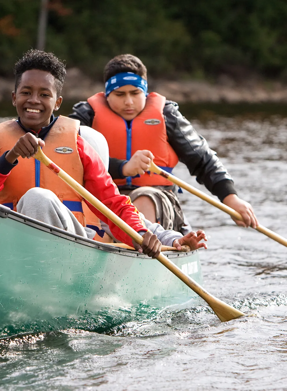 Two smiling youths paddling a canoe during Fall programming at Wanakita