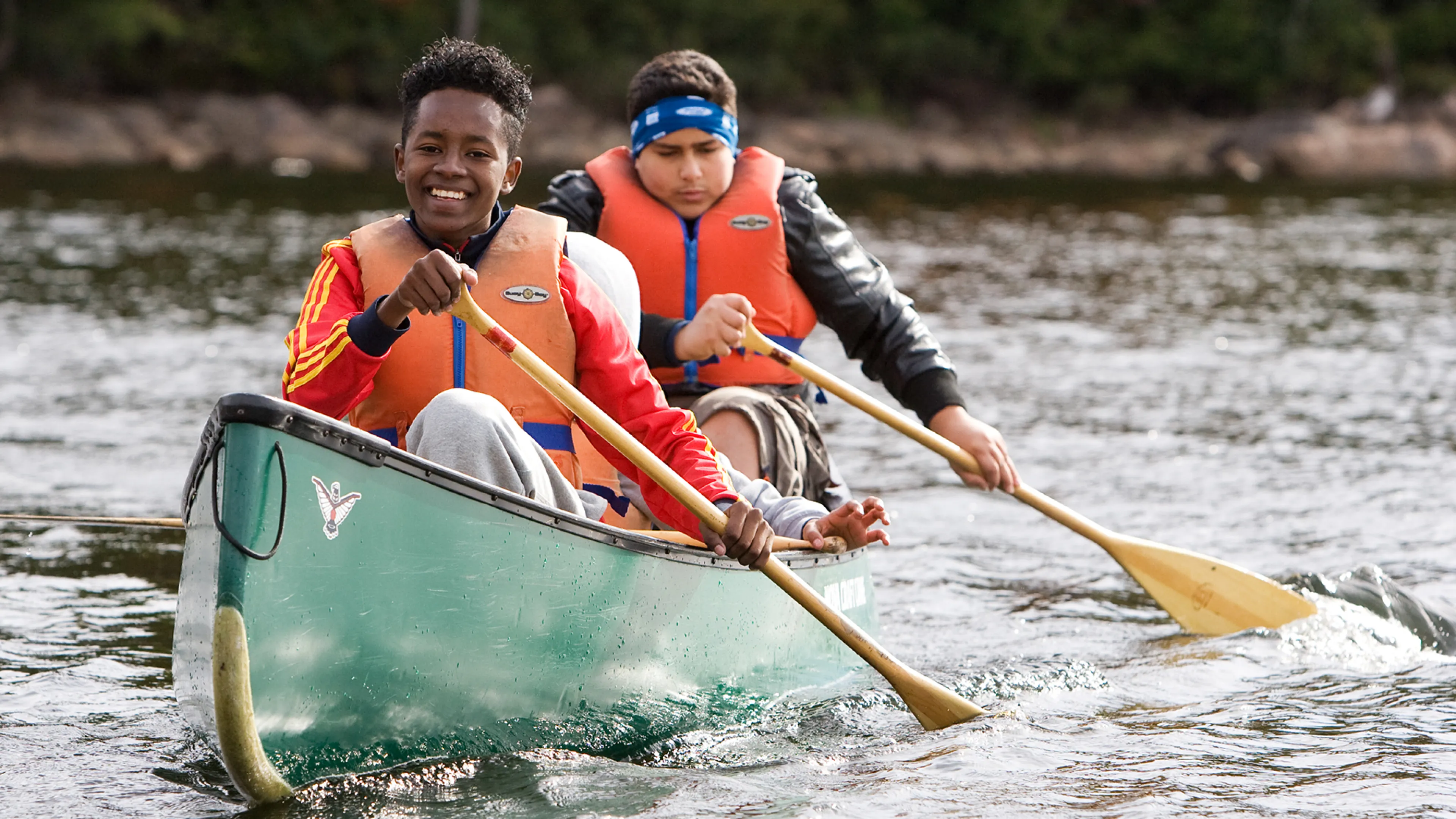Two smiling youths paddling a canoe during Fall programming at Wanakita
